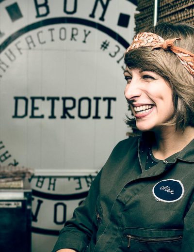 Woman smiling in front of a "Detroit" sign at our boutique hotel in Detroit