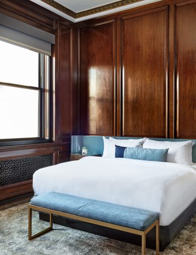 Bed and bench in a downtown Detroit hotel room with wooden walls