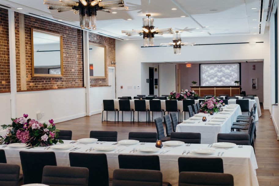 Long tables with place settings and flowers in the intimate event venue of the Detroit hotel.