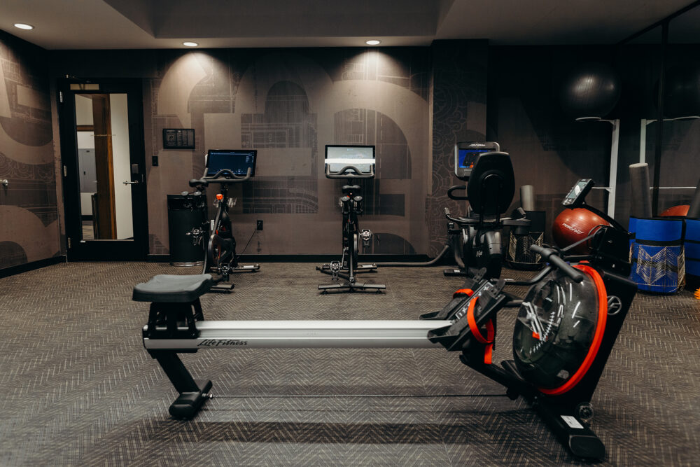 Recumbent and upright exercise bikes and a rowing machine at the fitness center of the Detroit hotel.