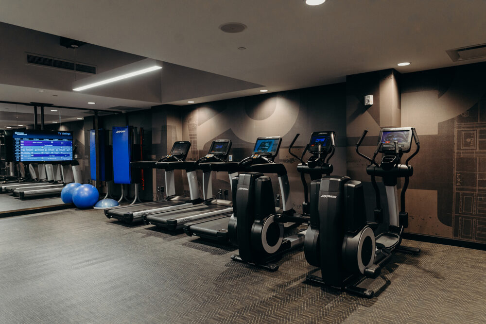 Treadmills, ellipticals, exercise mats, bosu balls, and a tv at the fitness center of the Detroit hotel.