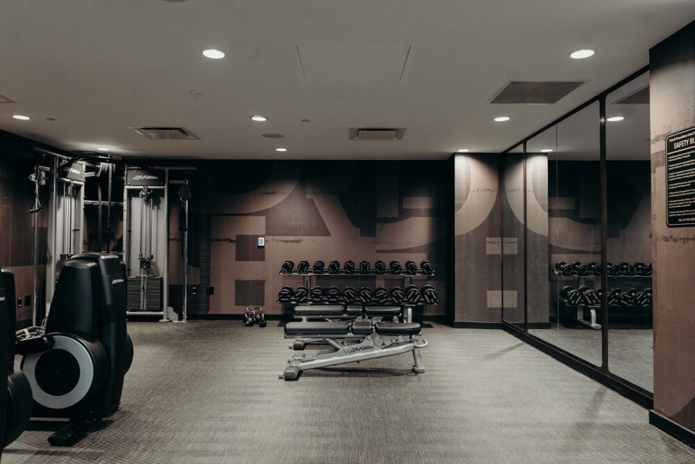 Elliptical, weight machine, free weights, and weight bench at our Detroit hotel's fitness center.