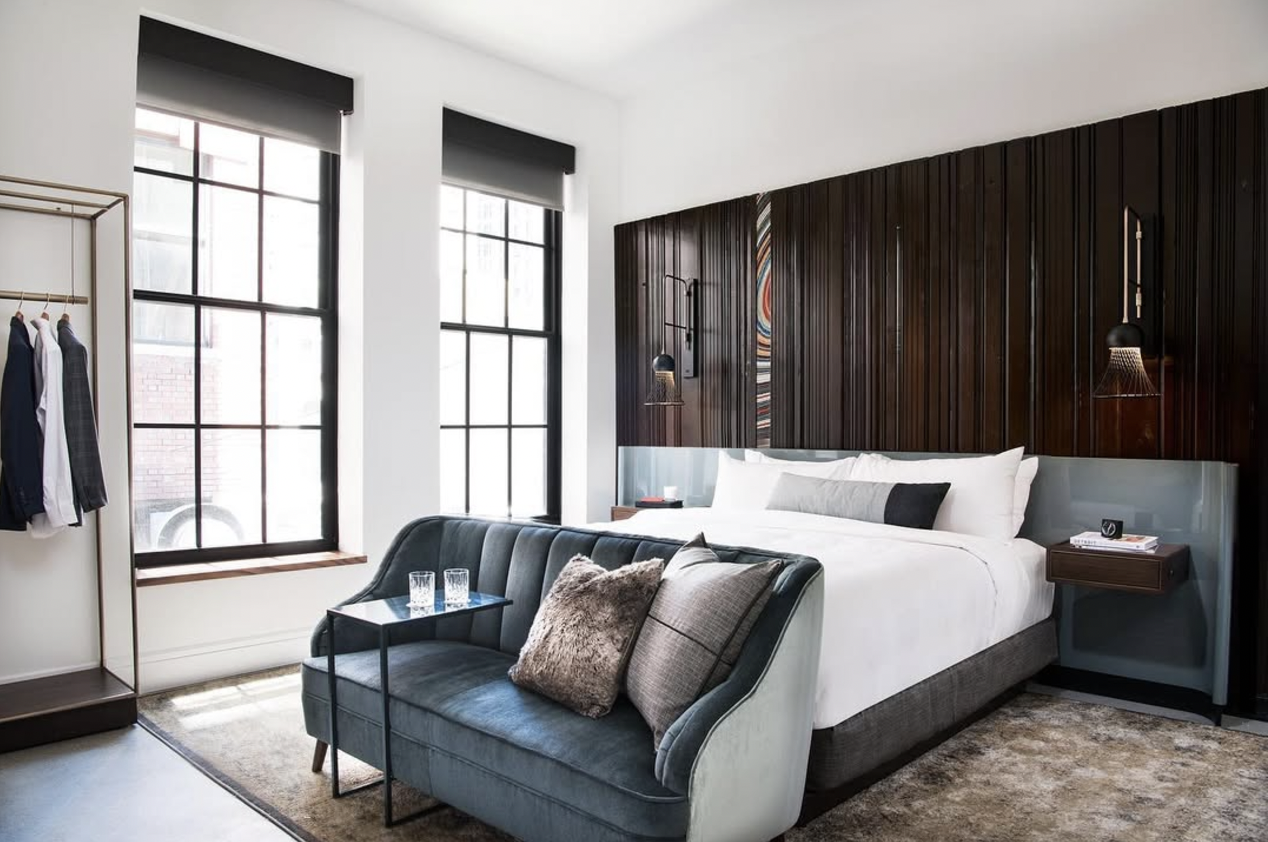 Double hotel bed dressed with white linen in a wooden boarded room