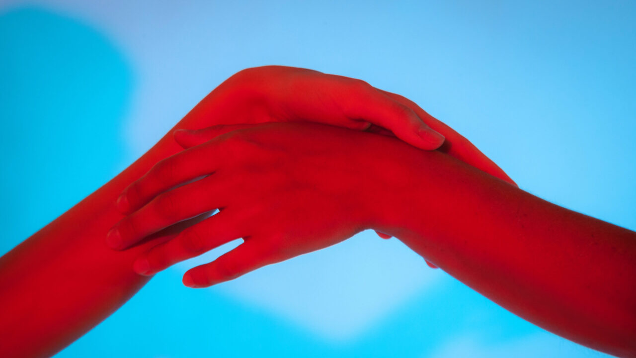 Two hands interlocked over a blue background, conveying connection or teamwork.