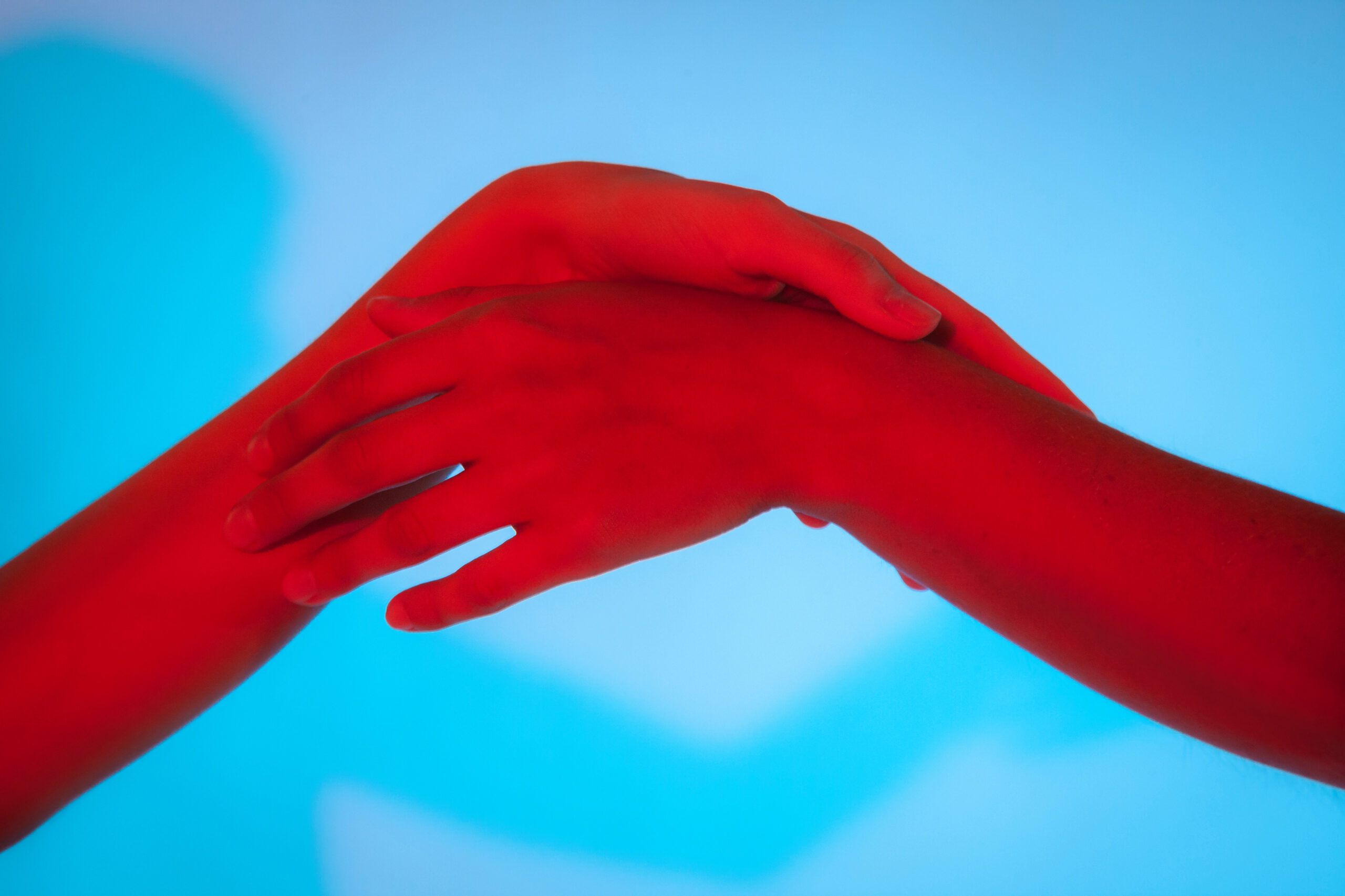 Two hands interlocked over a blue background, conveying connection or teamwork.
