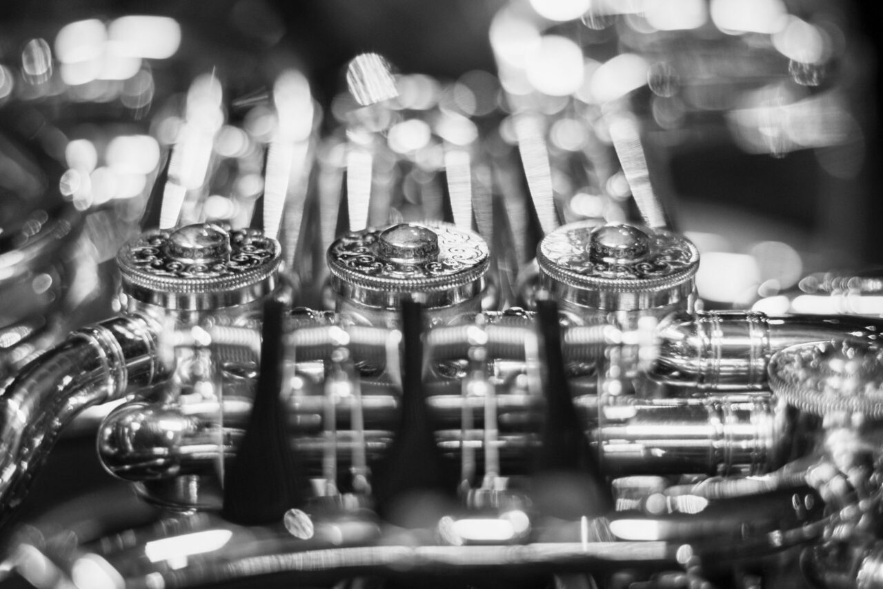 Close-up of ornate metal bottle caps with intricate patterns and a blurred, bokeh background in black and white.