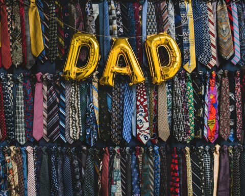 Wall of colorful patterned neckties with gold foil balloons spelling 50