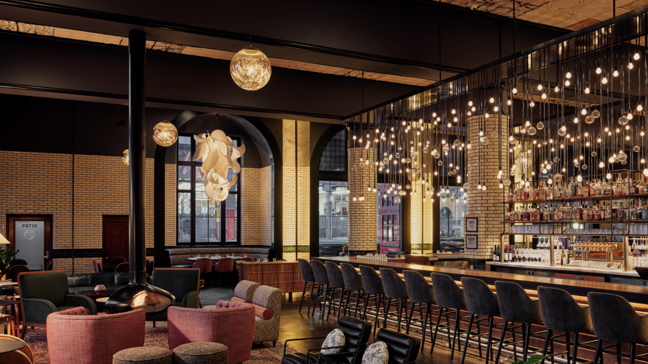 Luxurious bar lounge with brick walls, warm amber lighting, and plush orange and gray seating.