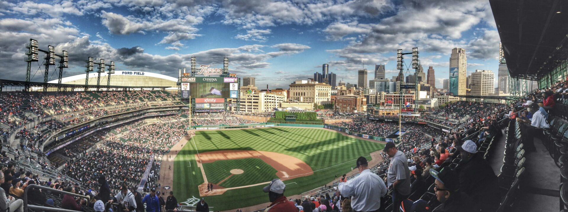 Panoramic view of a crowded baseball stadium with a urban skyline in the background.