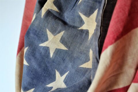 Close-up of a blue fabric with white star shapes and red fabric nearby, resembling part of a flag pattern.